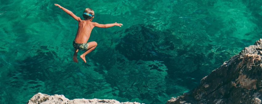 Boy dives over turquose water