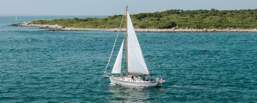 A sailboat travels past a green island off the shore of Martha's Vineyard.