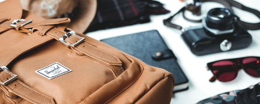 closeup photo of brown leather bag near sunglasses and shoes